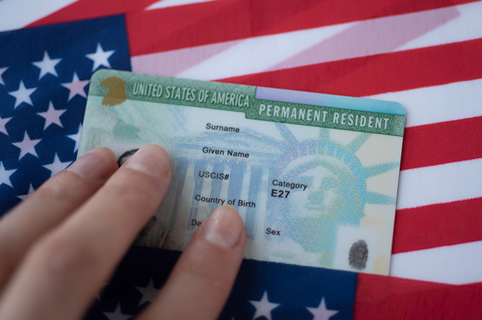 Mano Sobre Green Card con Fondo de Bandera de Estados Unidos